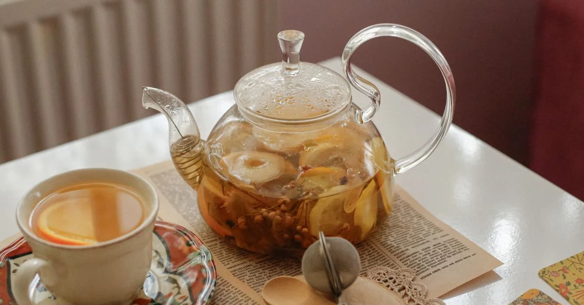 Théière en verre avec tisane, tasse, cuillères et décoration crée une ambiance chaleureuse à l'intérieur.