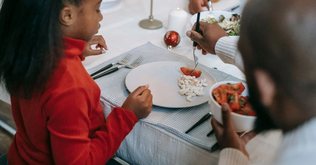Une joyeuse réunion de famille appréciant un dîner festif avec des pâtes et une salade à l'intérieur.