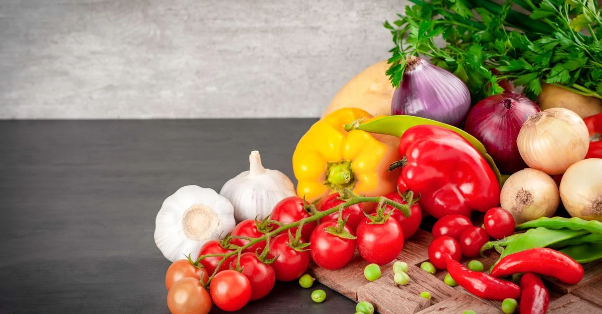 Une sélection vibrante de légumes frais, y compris des poivrons et des tomates, sur une planche en bois.