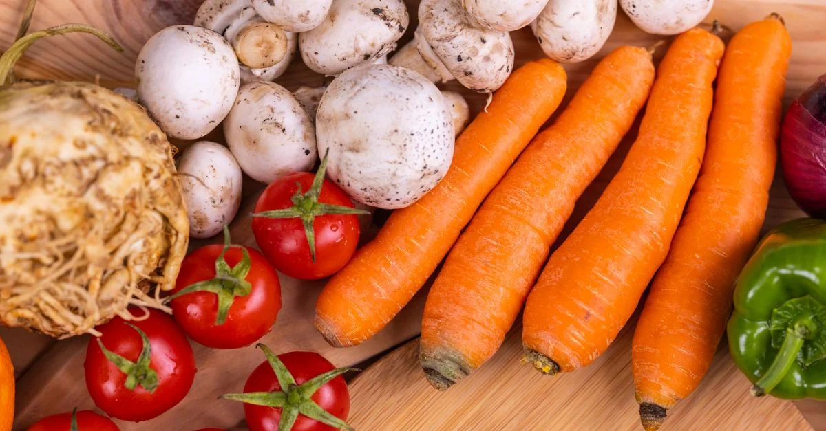 Une variété de légumes bio frais, y compris des carottes et des champignons, sur une table en bois.